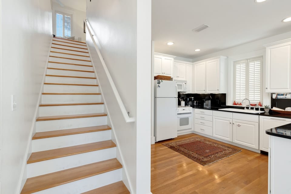 Your bright, modern kitchen flows seamlessly with elegant wooden stairs, creating a welcoming space for cooking and gathering.