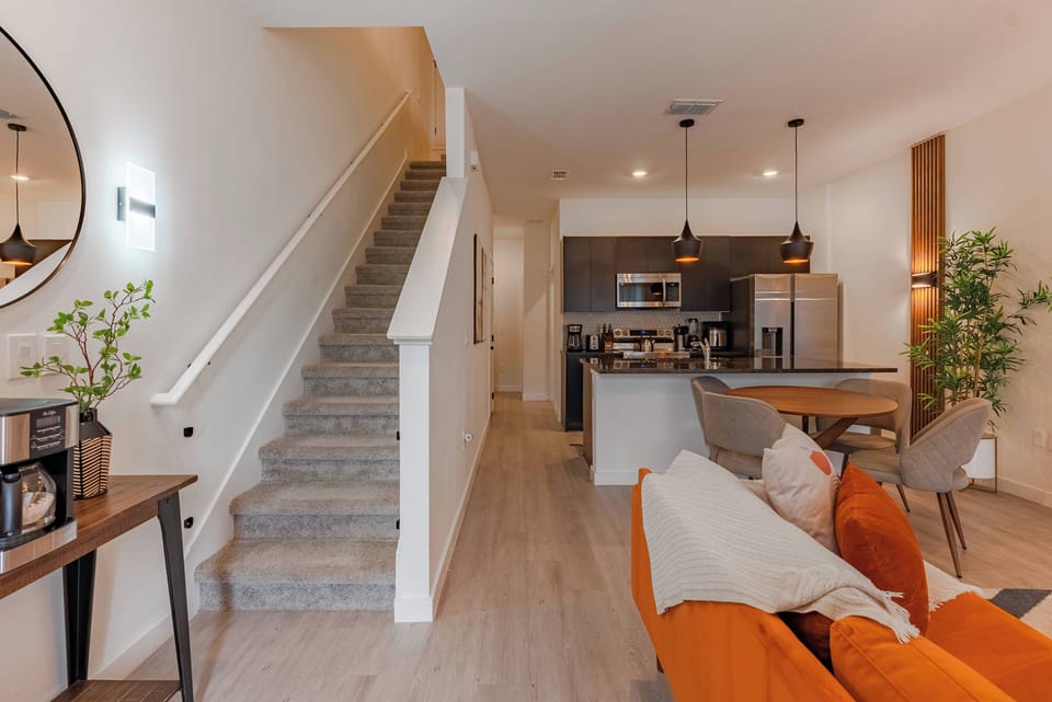 Experience a stylish living area with inviting orange furnishings and abundant natural light. The sleek kitchen features modern fixtures and a cozy dining space, perfect for sharing meals and laughter with loved ones.