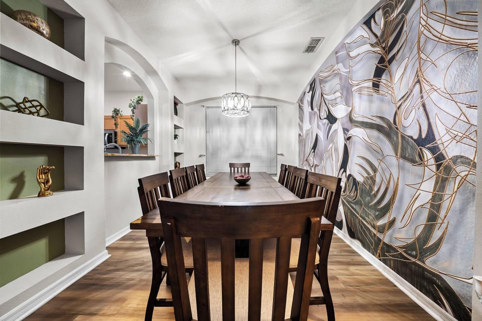 Come together at the spacious wooden dining table, surrounded by rich textures and a stunning mural. Bathed in soft light from the elegant chandelier, this inviting space is ideal for shared meals and lively conversations.
