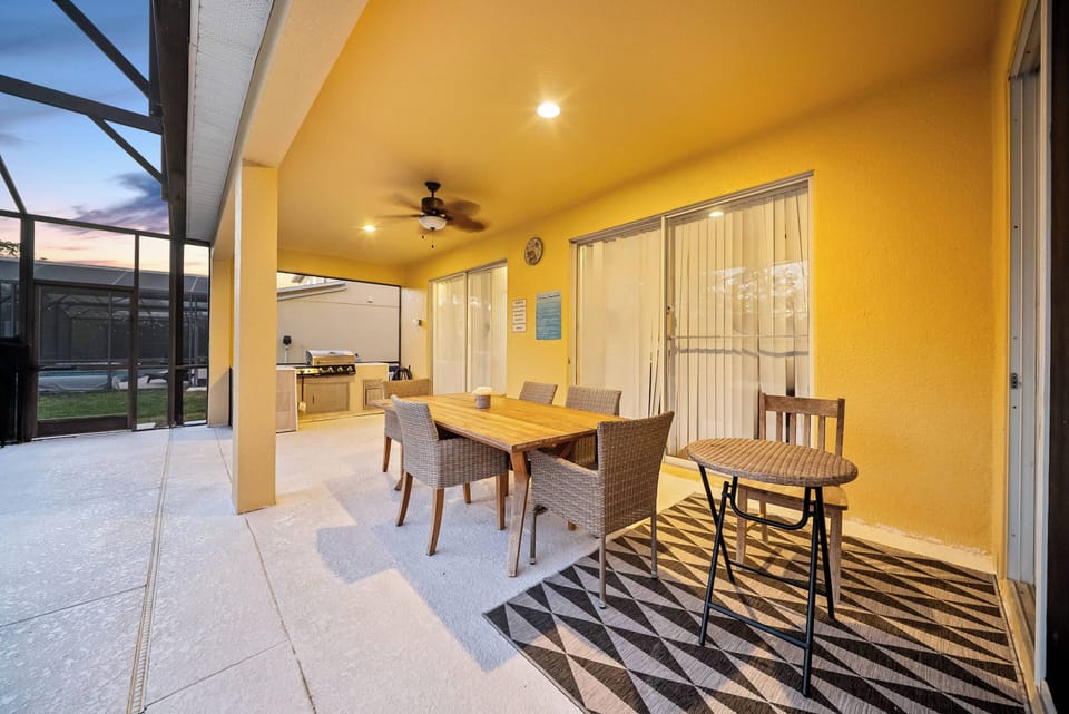 Enjoy your private outdoor dining area with a stylish wooden table and comfy wicker chairs. The warm yellow walls and patterned rug create a cheerful and modern ambiance for your al fresco experience.