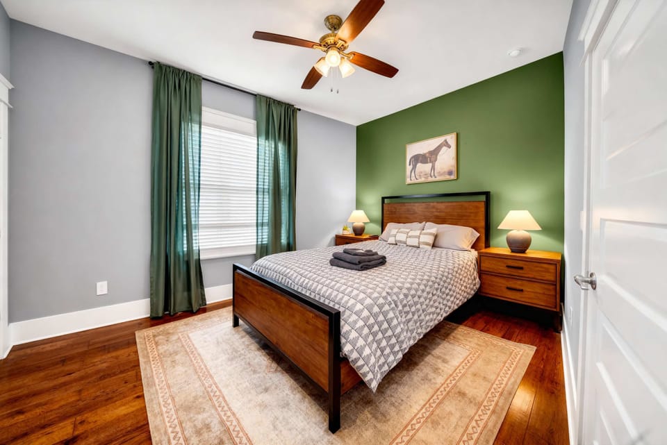 A queen bed paired with warm wood flooring and a soft rug create a restful retreat. Ceiling fan keeps it cool when Nashville heat rolls in