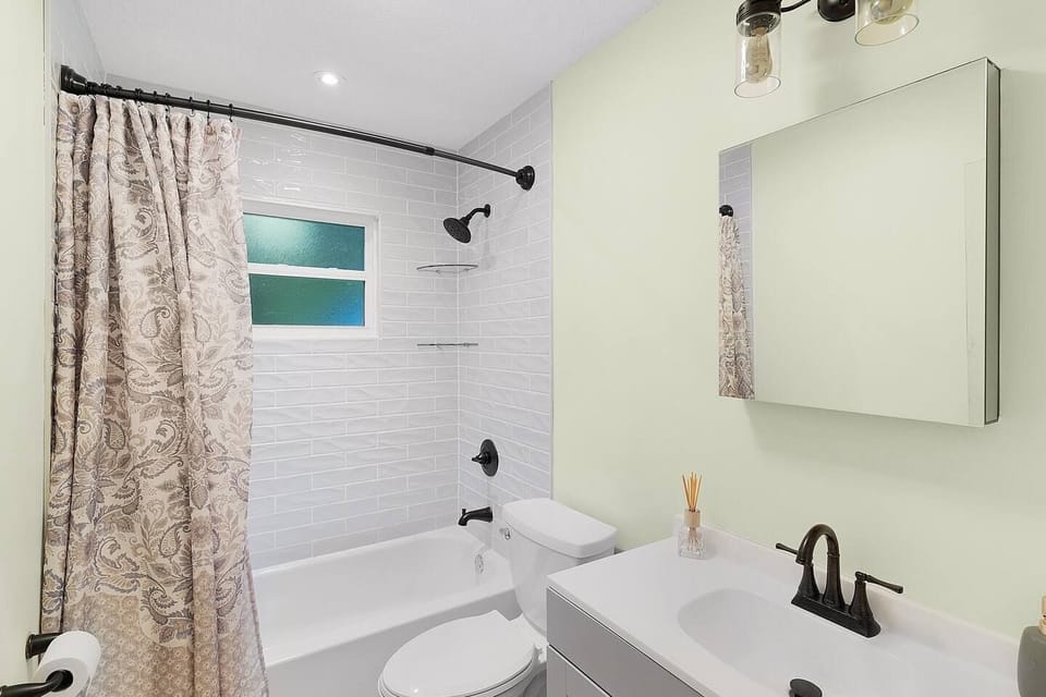 Bathroom featuring a vanity, toilet, and subway-tiled bathtub-shower combo.