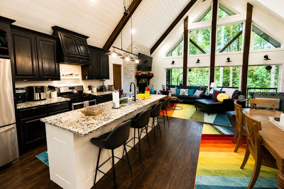 Open‑concept kitchen and dining space with bar seating and forest views through 