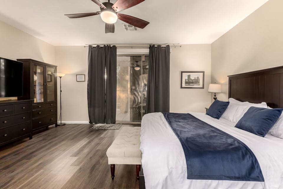 Spacious bedroom with dark wood furnishings and sliding glass door access.