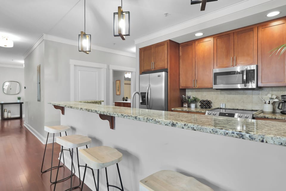 Modern kitchen with granite countertops, stainless steel appliances, and breakfast bar seating.