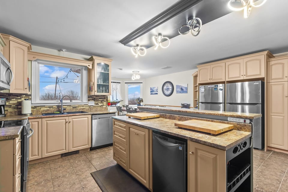 Enjoy a second angle of the kitchen showcasing generous cabinetry, built-in microwave, and cozy bar stools—perfect for morning coffee. 
