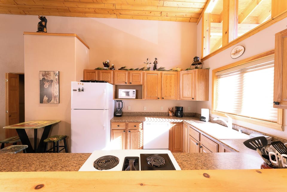 Your fully equipped kitchen features warm wood cabinetry, granite counters, and everything you need to prepare meals with natural light streaming through large windows.