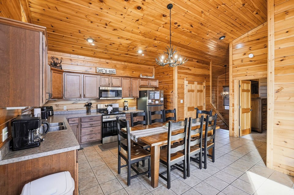 Gather around this rustic dining table where warm wood surrounds you and the antler chandelier sets the perfect cabin mood for memorable meals.