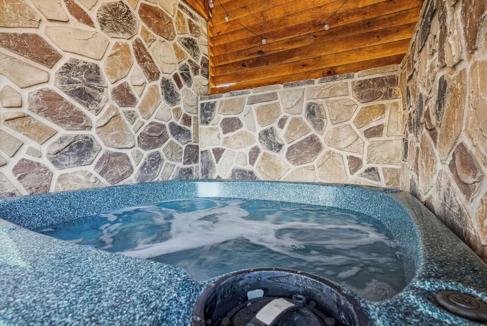 Unwind in your private hot tub surrounded by rustic stone walls and warm wooden beams overhead.