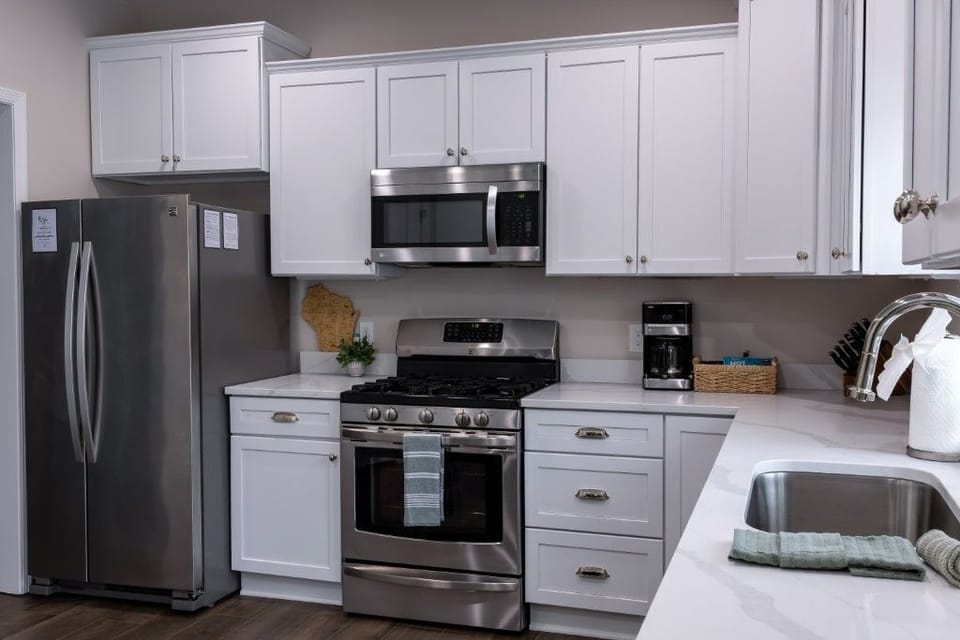 The modern kitchen, featuring sleek stainless steel appliances and pristine white cabinetry, offers a functional yet inviting space for family cooks to come together and create delicious meals while enjoying quality time.