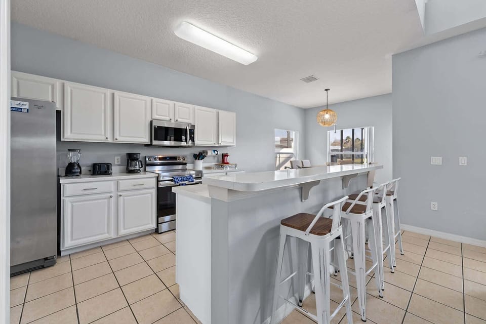 Modern kitchen with stainless steel appliances and a breakfast bar with seating for four.