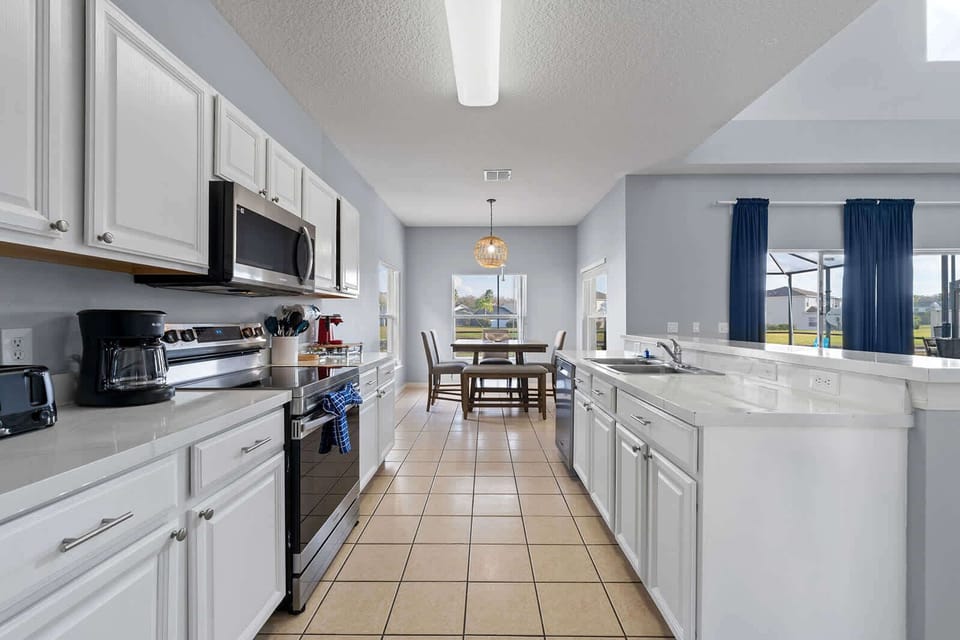 Bright kitchen with white cabinetry and a dining area overlooking the backyard.