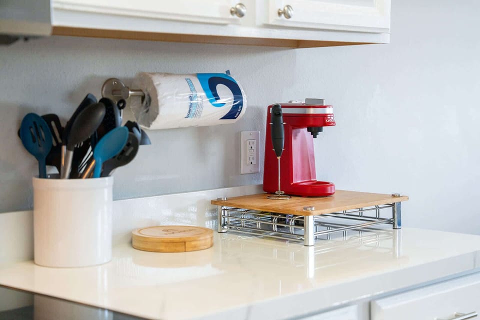 A clean kitchen counter with a red coffee maker and organized utensils for convenient meal preparation.
