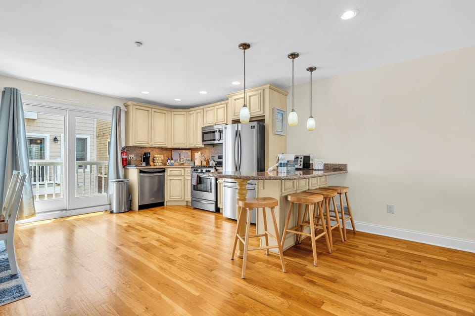 Bright open kitchen with breakfast bar, hardwood floors, and deck access
