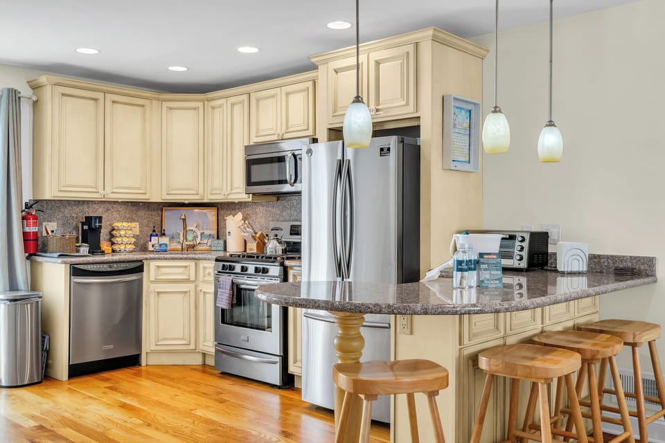 Bright kitchen with granite counters, stainless appliances, and bar seating