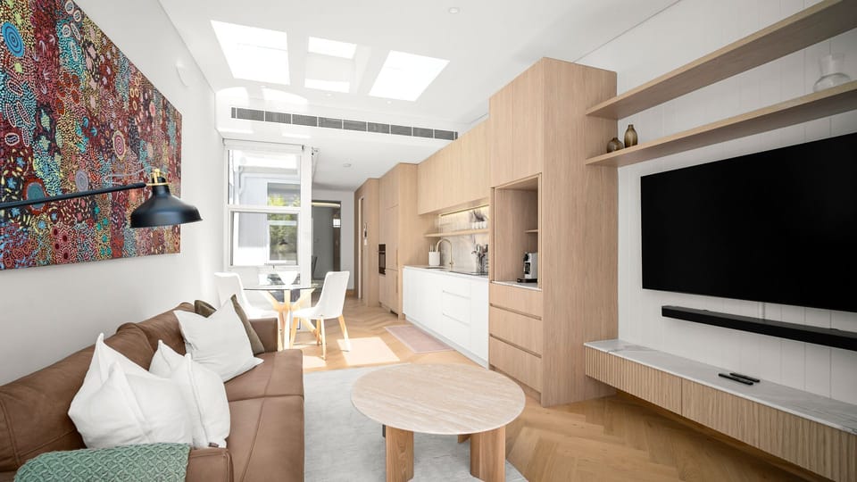 Open-plan living area with sofa, wall-mounted TV, and skylights