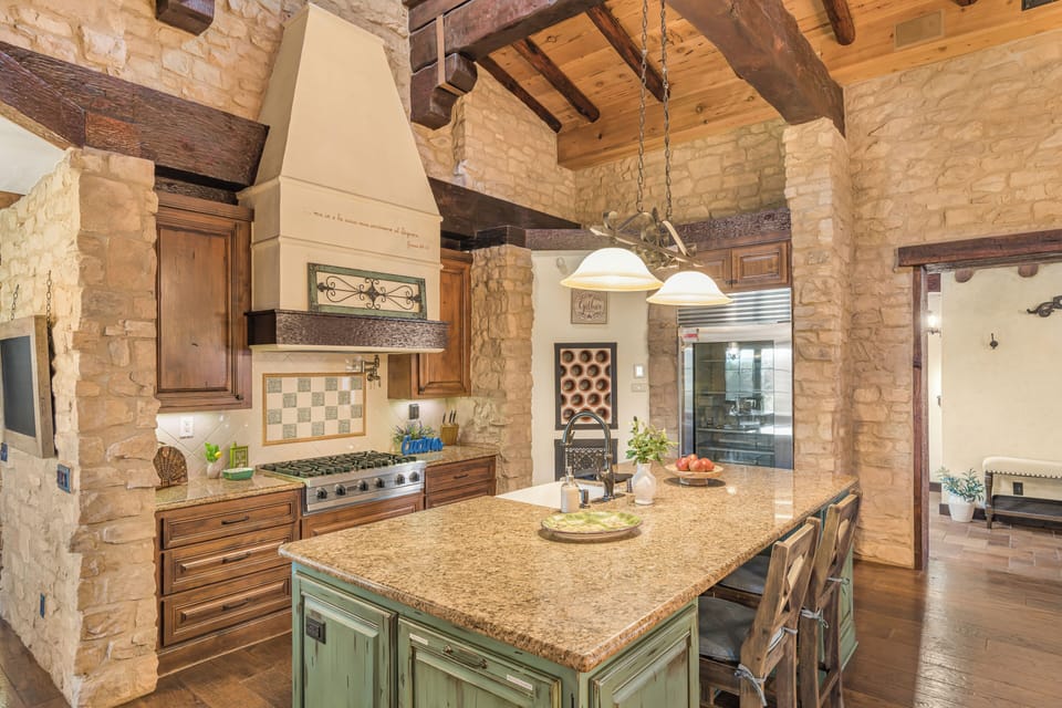 A chef-inspired kitchen blends stone walls, exposed beams, and a statement island—perfect for slow mornings and wine-country feasts.