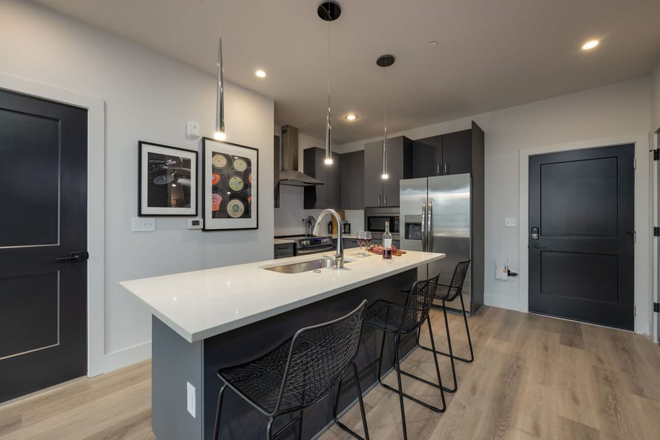 Full view of the modern kitchen with stainless steel appliances and stone countertops.