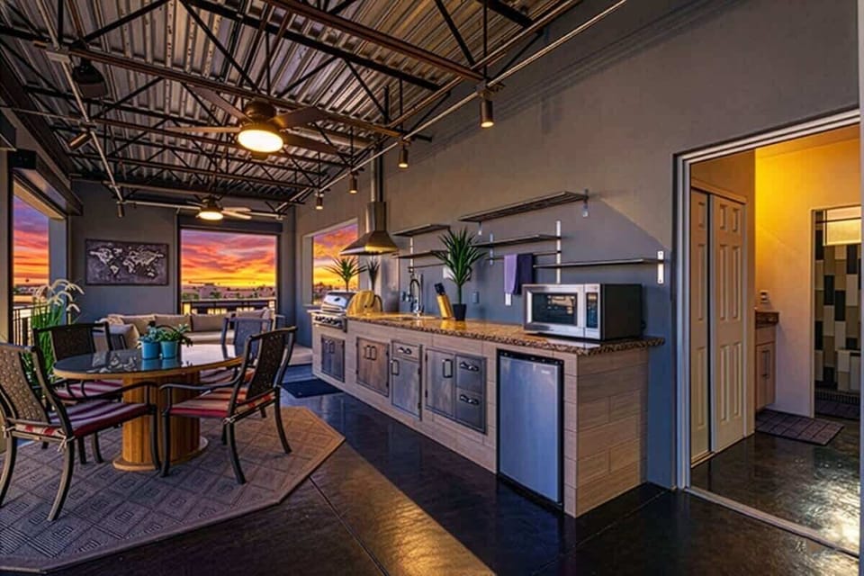 Rooftop deck boasts an outdoor kitchen with grill, sink, mini fridge, and cooking utensils, outdoor dining for four, a fireplace, smart TV, and three furnished lounging areas, and breathtaking panoramic views of Old Town Scottsdale.