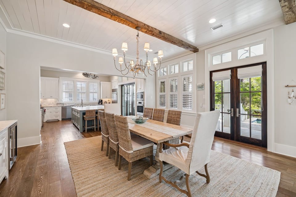 Gather around this stunning dining table beneath exposed beams and elegant chandelier light, where your family meals become cherished memories.