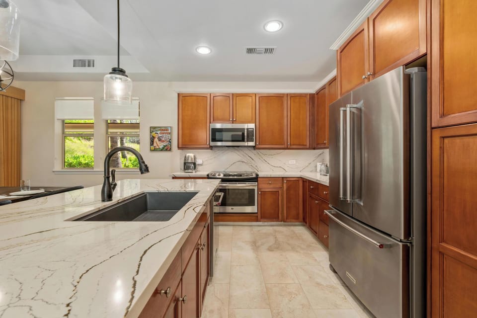 Your fully equipped kitchen features stunning marble countertops, stainless steel appliances, and warm wood cabinetry perfect for preparing memorable meals together.
