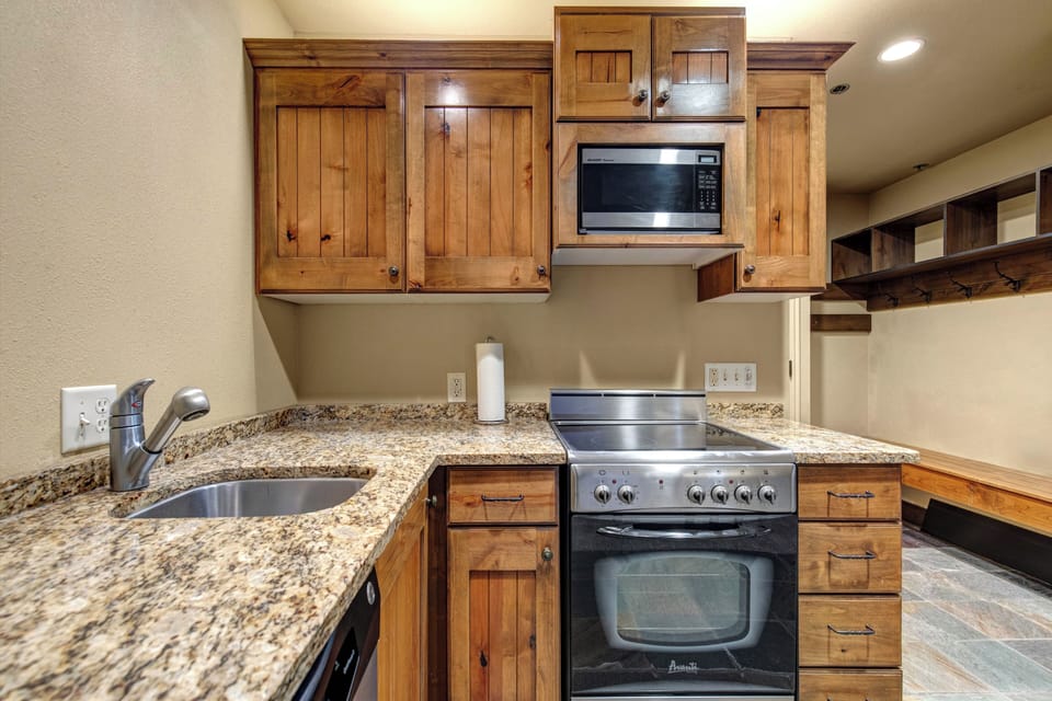 Your fully equipped kitchen features rustic wooden cabinets, granite countertops, and stainless steel appliances.