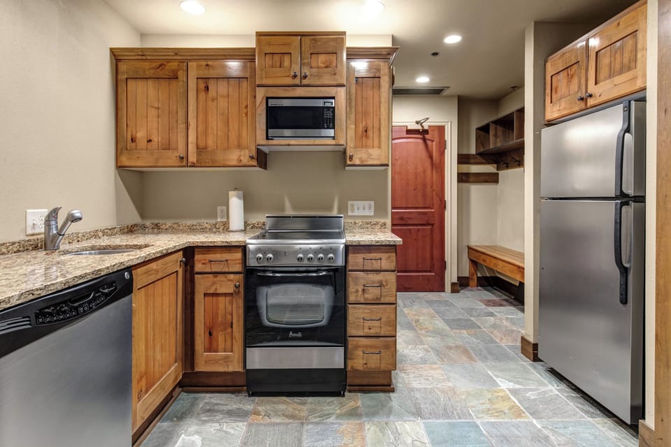 Cook your favorite meals in this fully-equipped kitchen featuring granite countertops and stainless steel appliances.