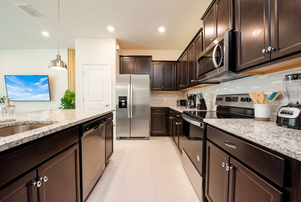 Step into this stylish kitchen featuring rich, dark cabinetry that contrasts beautifully with the light granite countertops. Enjoy modern appliances and ample space, making meal prep a delight in this well-lit culinary haven.