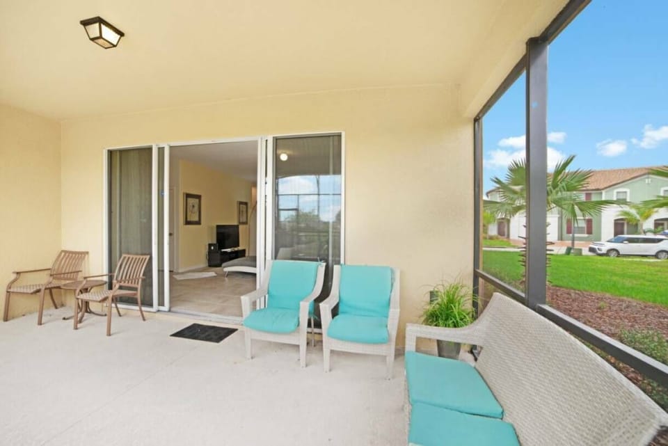 Step outside to a lovely patio with bright turquoise chairs and a cozy bench, ideal for your morning coffee or evening relaxation. The screened enclosure lets in fresh air while keeping the area comfortable and bug-free.