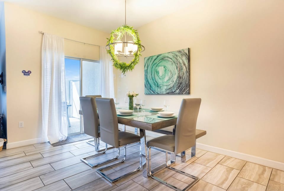 Enjoy meals in this bright dining area featuring modern chairs and a stylish wooden table. The artistic wall decor and warm light fixture add charm, while natural light fills the space through the sliding glass doors.