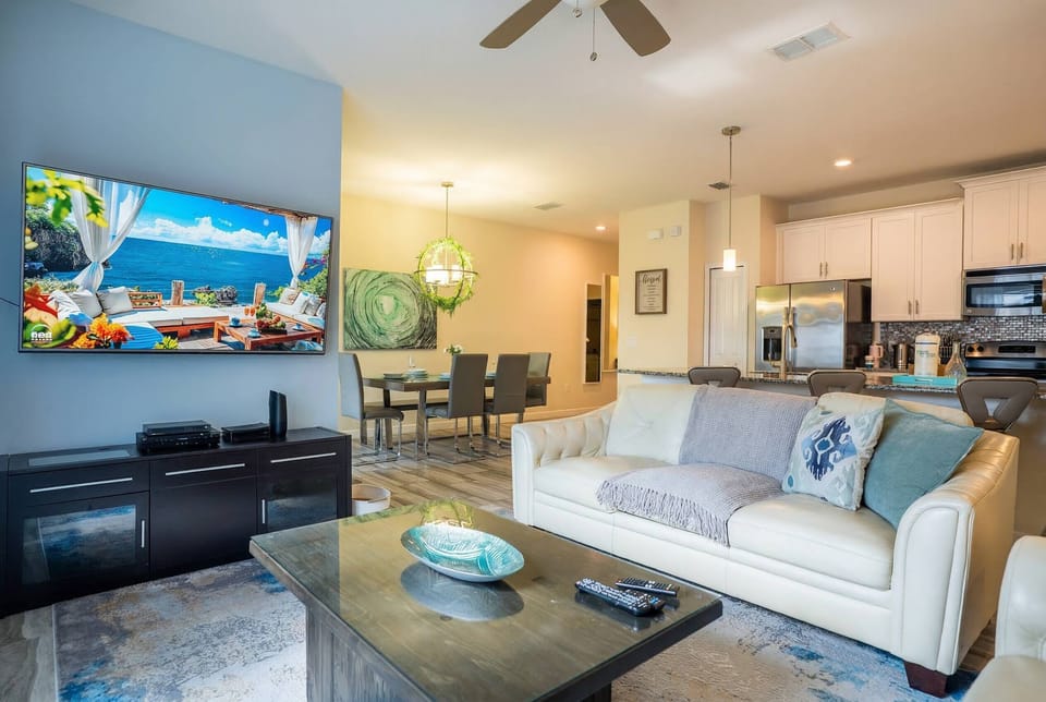Welcome to a stylish living area featuring a plush white sofa perfect for relaxation, a chic coffee table, and vibrant artwork. The open layout connects this inviting space to a modern kitchen for ultimate comfort and style.