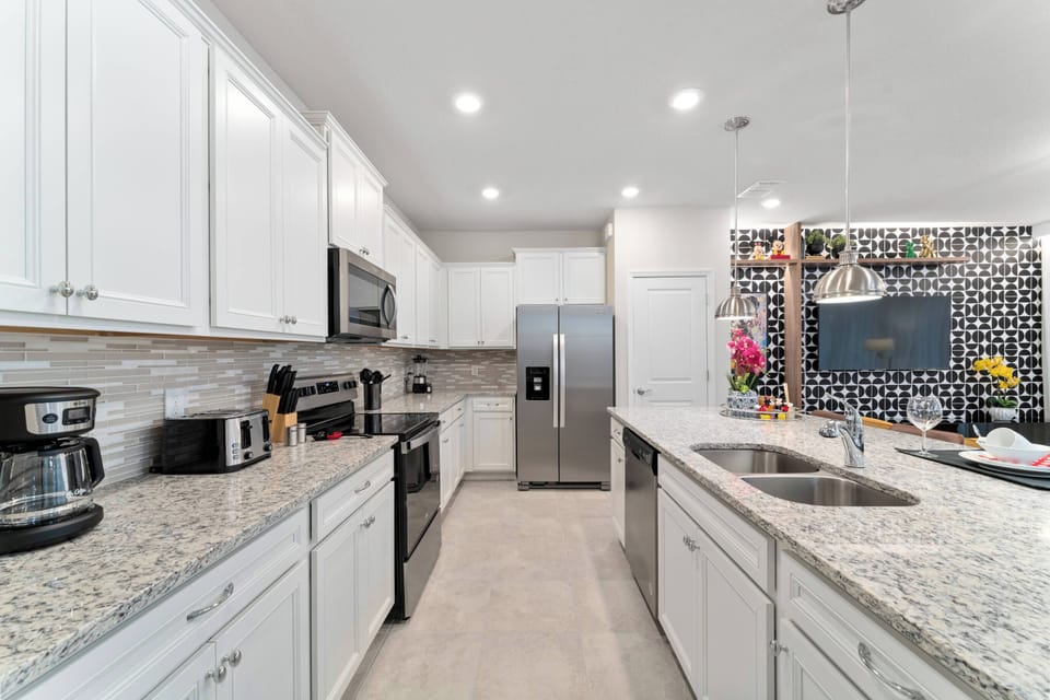 Experience a chic kitchen featuring bright white cabinets and beautiful granite countertops. With modern stainless-steel appliances and a lively accent wall, this inviting space is perfect for your culinary adventures!