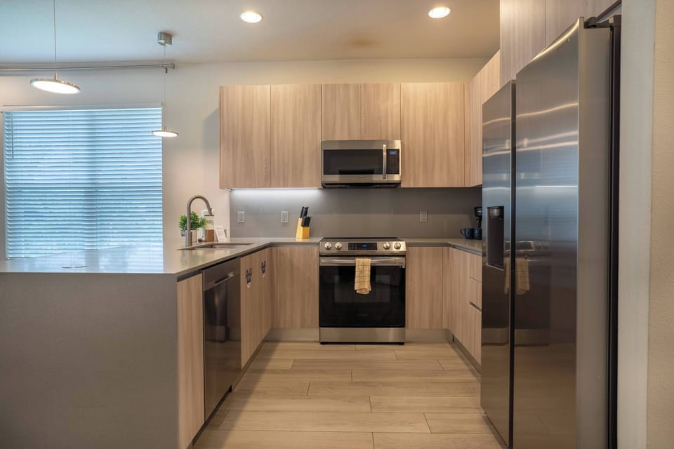 This inviting kitchen boasts sleek stainless steel appliances and warm wood cabinetry, making it perfect for meal prep. With its modern layout, stylish lighting, and spacious countertop, it's a great place for your culinary.