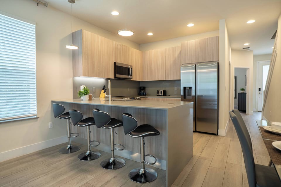 This kitchen features modern cabinetry and a spacious island perfect for casual meals or morning coffee, while the soft light from the large window enhances the inviting atmosphere for your culinary adventures.