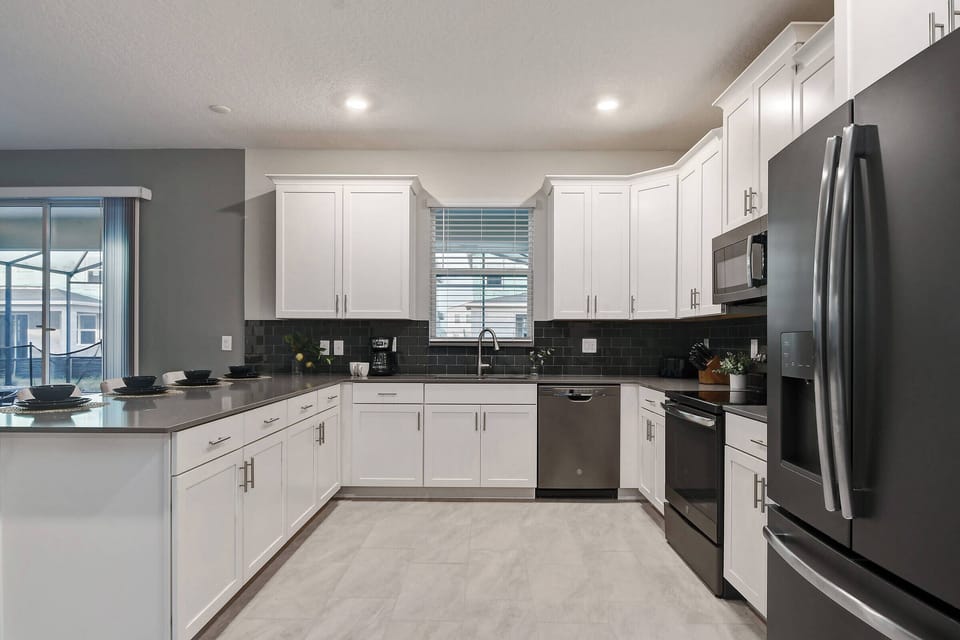 This contemporary kitchen boasts sleek white cabinets and dark granite countertops, creating a beautiful contrast. With natural light illuminating modern appliances and a spacious layout, it's perfect for your culinary adventures.