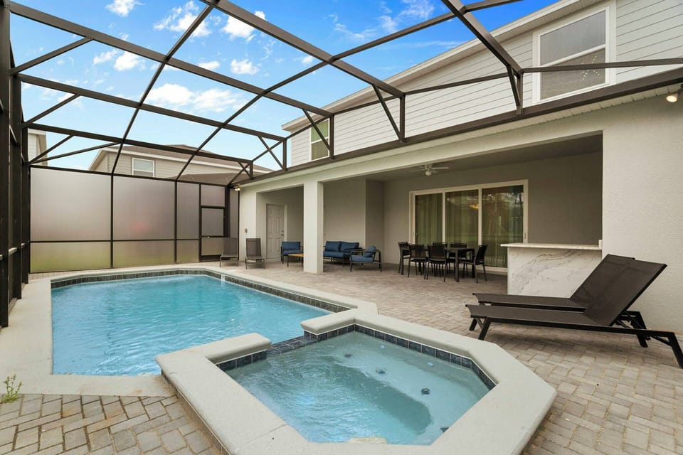 Step into your own private oasis with a sparkling pool and a relaxing spa, all framed by a sleek screened enclosure. The spacious patio invites you to unwind on stylish lounge chairs, perfect for sun-soaked afternoons.