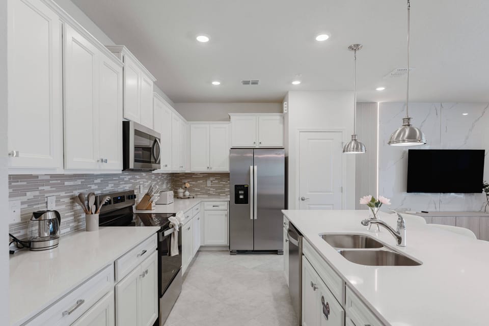 This bright kitchen features sleek white cabinetry and beautiful quartz countertops, creating a polished space for your cooking. Modern stainless-steel appliances and soft pendant lighting add to the warm, inviting atmosphere.