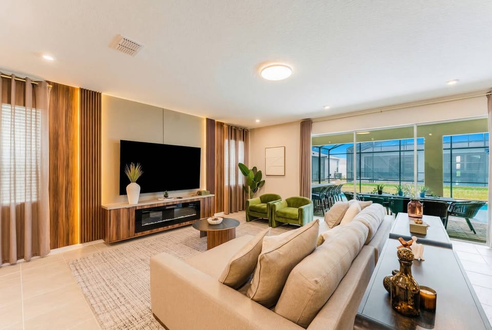 Experience a bright and stylish living area with a modern sofa and plush cushions. The warm wood accents and vibrant green chairs offer a cozy, sophisticated space ideal for relaxation and connection.