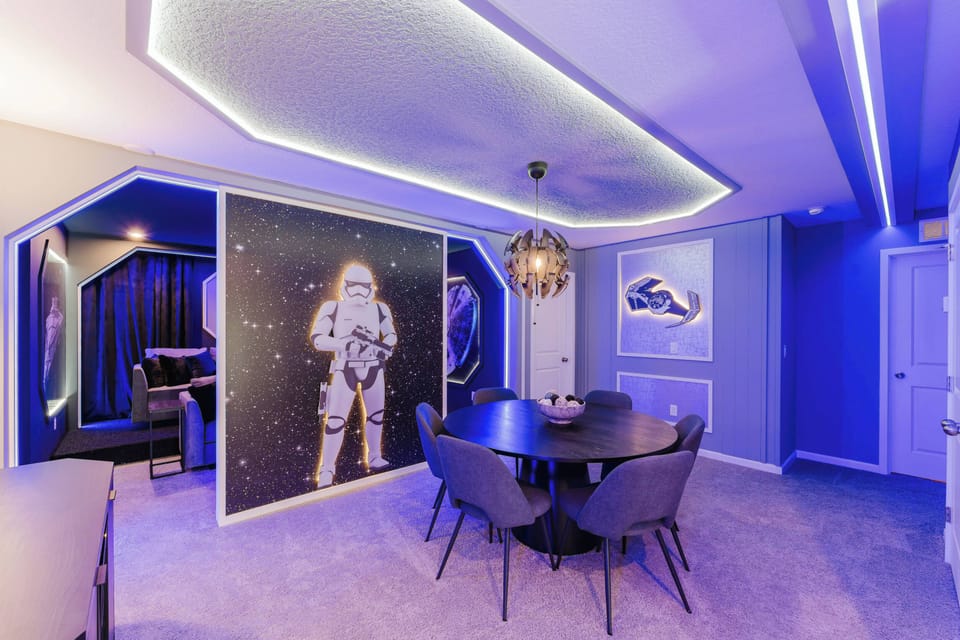 Enter a vibrant dining area bathed in soft blue light, featuring a stylish round table perfect for gatherings. The whimsical astronaut mural adds charm, while cozy seating guarantees comfort during every delightful meal shared.