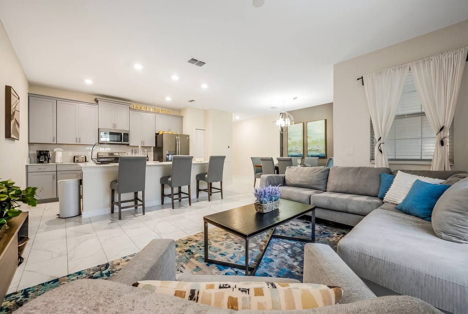 Experience a beautifully designed living space featuring a spacious layout with a large sectional sofa and sleek coffee table. The modern kitchen, with stylish bar seating, is ideal for casual gatherings, all enhanced by warm.