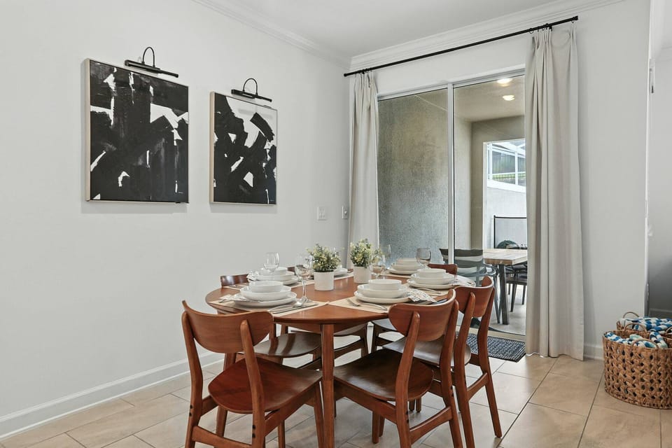 Enjoy a bright and inviting dining area with a charming wooden table, warm natural tones, and modern black-and-white wall decor, all illuminated by large windows that let in abundant sunlight for a delightful dining experience.