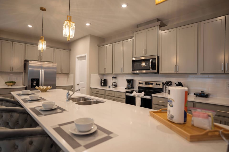 Discover an elegant kitchen with a sleek white countertop, soft gray cabinetry, and stylish pendant lighting. The spacious island is perfect for gatherings, while modern appliances make your culinary adventures a breeze.
