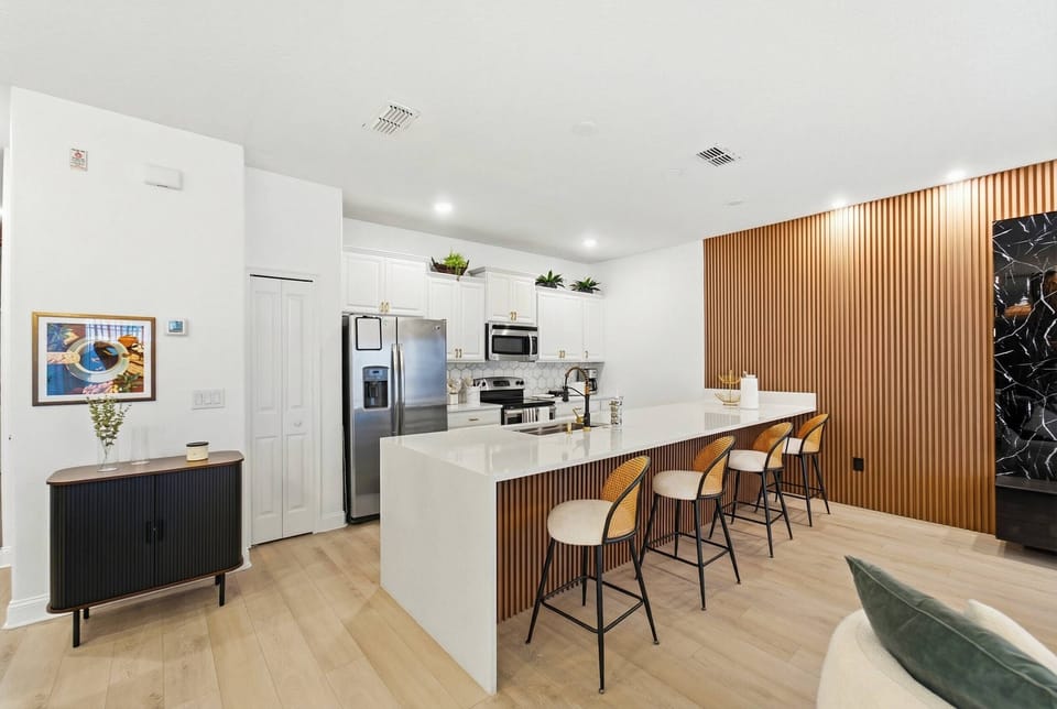 Enjoy a beautifully designed kitchen featuring a sleek marble island and stylish bar stools, perfect for casual gatherings. The warm wood accents create a bright, inviting atmosphere for a delightful culinary experience.