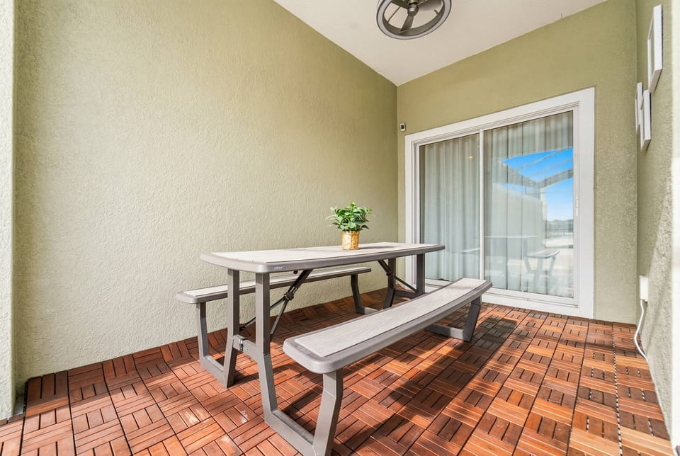 Enjoy meals al fresco in this charming outdoor dining area, featuring a sturdy wooden table and benches. The warm tile flooring and soft green walls create a cozy atmosphere perfect for relaxing and unwinding.