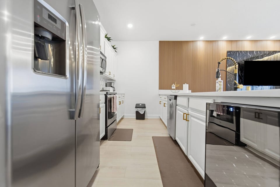 Discover a stylish kitchen featuring stainless steel appliances and chic cabinetry, designed for culinary adventures. The warm wooden accents and sleek countertops create a welcoming space ideal for shared meals and laughter.