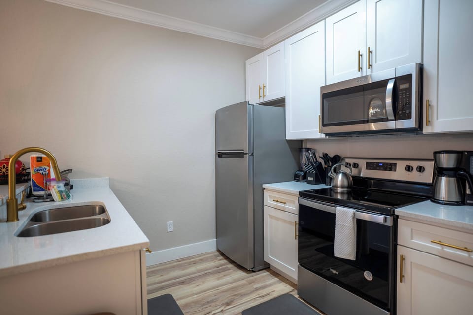 Step into a well-equipped kitchen featuring sleek stainless steel appliances and bright white cabinetry that creates a clean, airy feel. The subtle wood flooring adds warmth, making it a delightful space for cooking and gathering.