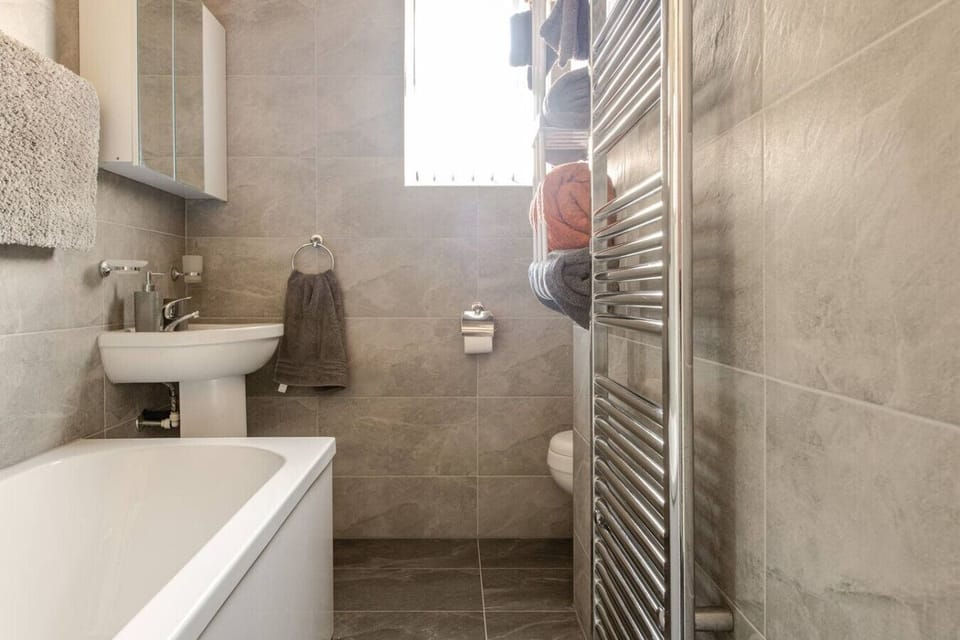 Bathroom overview with bathtub, sink, and towel radiator.
