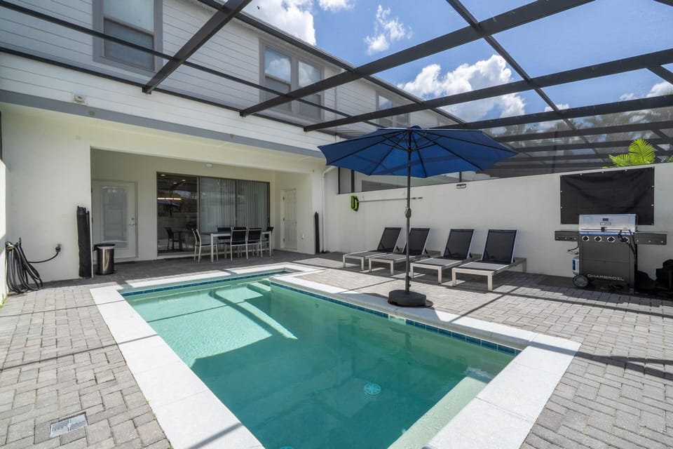 Sunlit poolside patio with lounge chairs and outdoor dining