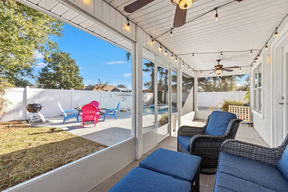 Screened lanai with pool view, comfy seating, grill & string lights
