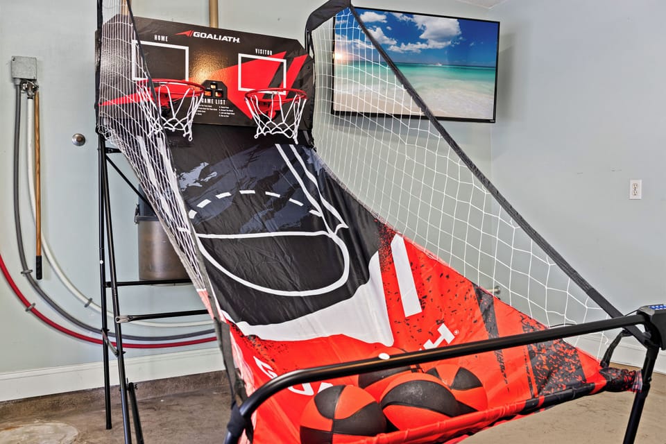 Garage game room with dual-hoop basketball and wall-mounted TV